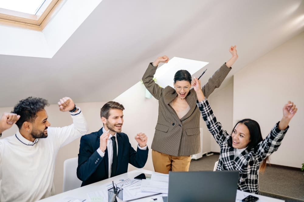 Business-win Group of office workers celebrating in front of a laptop.