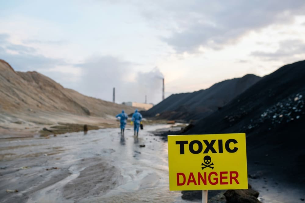 Toxic Sign saying 'Toxic/Danger' in front of barren landscape and factory.