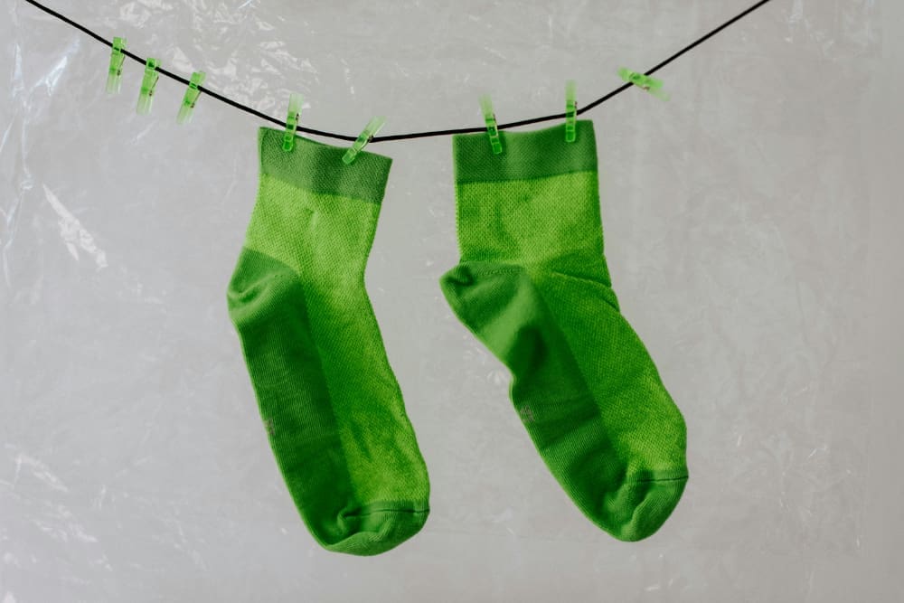 Greenwashing avoidance Two green-dyed socks hanging on a washing line.
