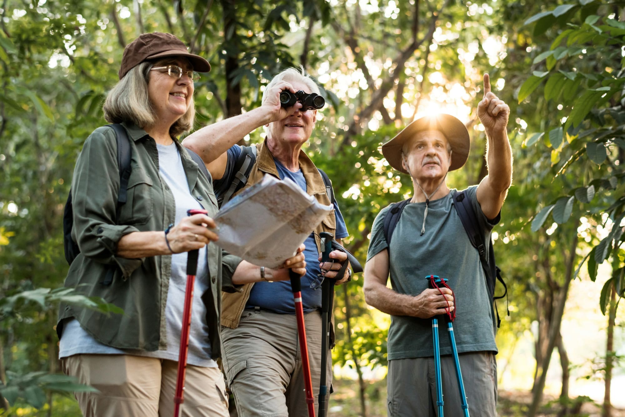 Three people in the jungle looking at a map and using binoculars to search for something.