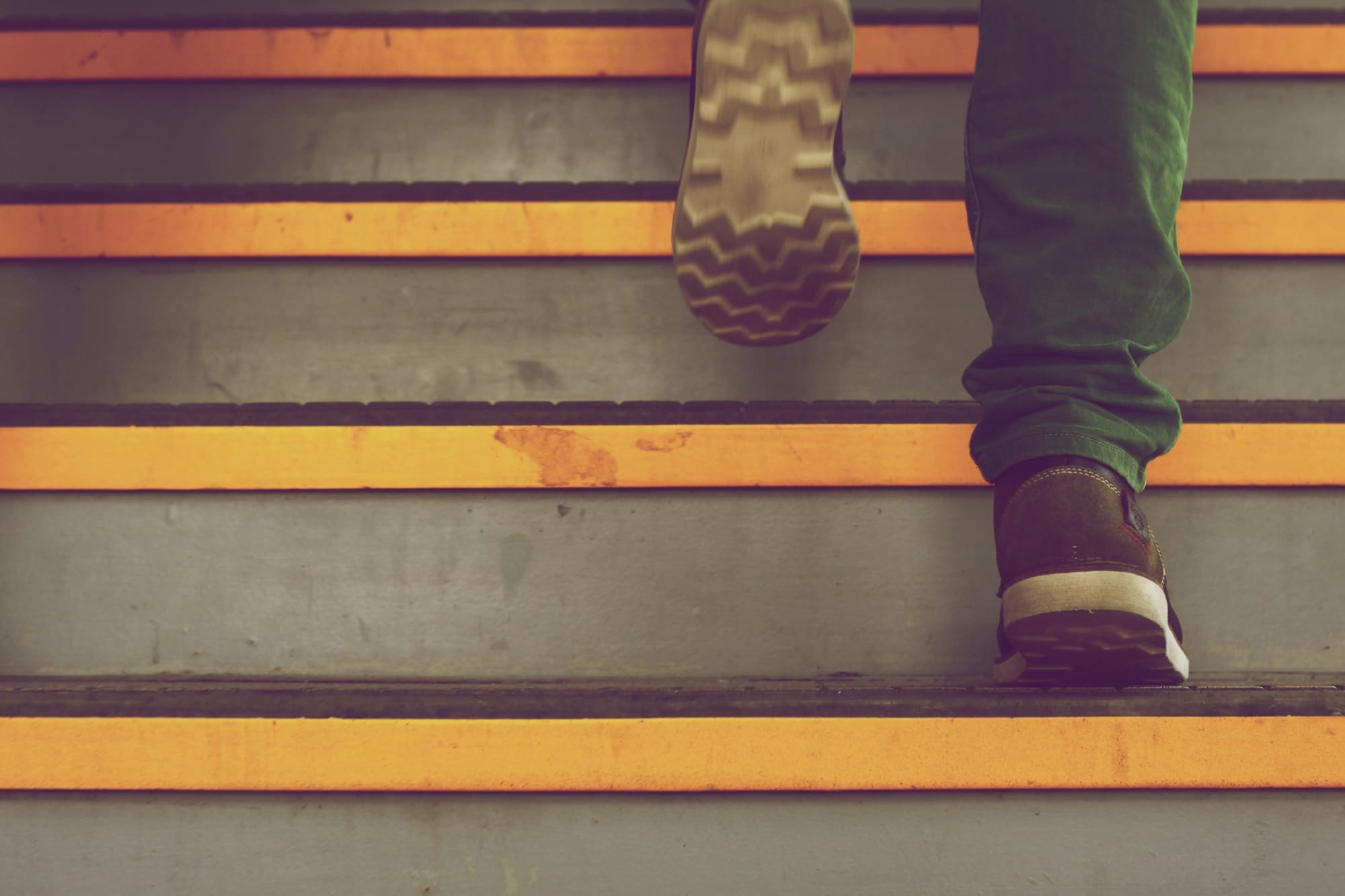 EcoVadis First Step Person on stairs, with bottom half of right leg planted, and left foot raised above to take the next step.